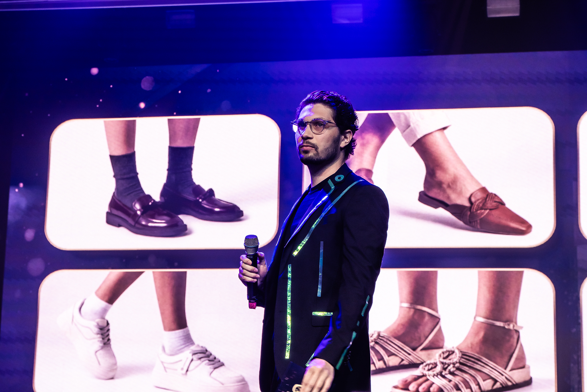 Kevin Botelho no palco com um microfone durante uma convenção corporativa.